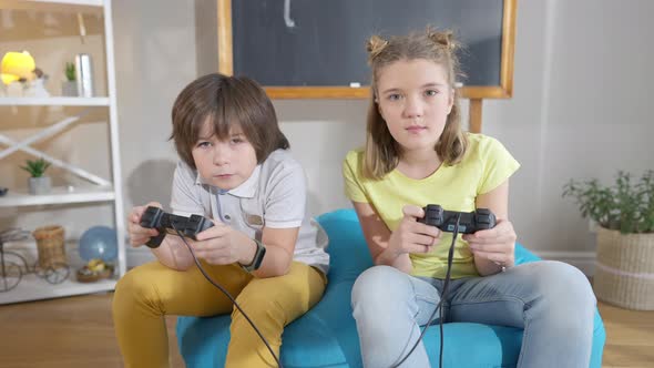 Happy Absorbed Caucasian Boy and Girl Using Game Consoles Playing Video Games alt