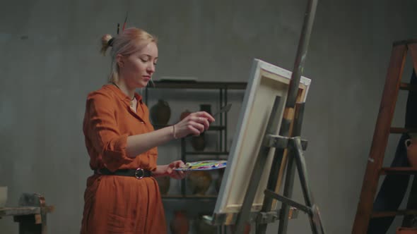 Female Artist Creating Picture Using Palette Knife alt