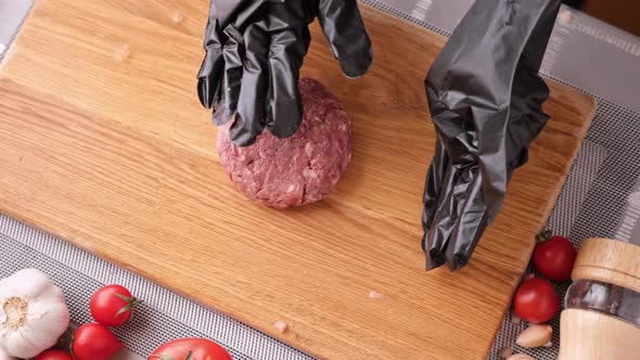 Woman Chef in Black Gloves Prepares Cutlets at Domestic Kitchen on a Wooden Cutting Board alt
