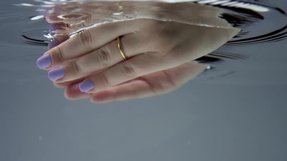 Womans Hand Immerse Into the Clear Water To Take Som Water. Underwater View