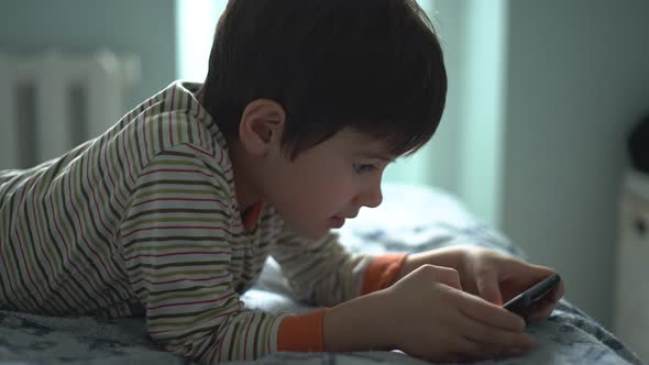 The Boy is Actively Playing Smartphone Alone in the Room