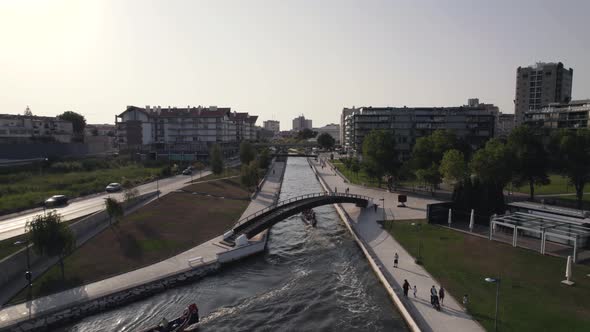 Establishing shot of drone following a moliceiro boat cruising through the narrow canal in Aveiro. alt