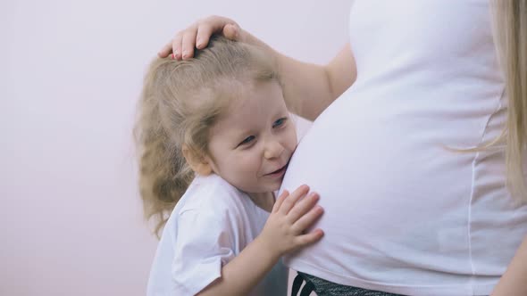 Pretty Girl Talks to Pregnant Mommy Touching Belly in Room alt