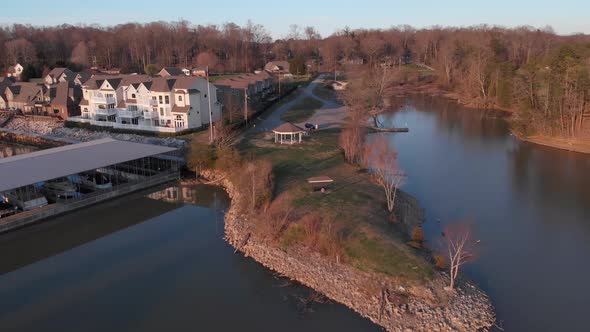 Aerial drone footage flying over lake towards a point of land with calm water and nice houses alt