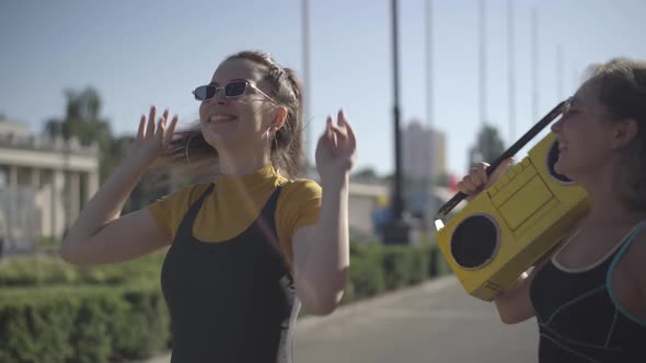 Two Positive 1980s Women in Sunglasses Dancing To Retro Disco Music From Vintage Yellow Tape alt