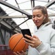 Young woman basketball player with headphones holding ball using smartphone. - VideoHive Item for Sale