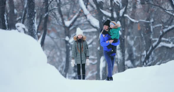 Mom and Children are Walking Along a Snowy Road in the Winter in the Forest Everyone is Smiling and alt