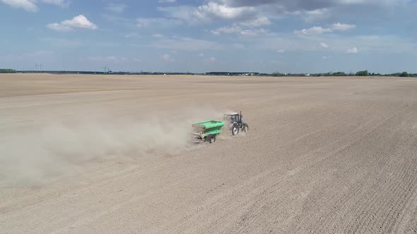 Aerial View  Video of Tractor with Fertilizer Trailer Fertilizes the Field After Planting alt