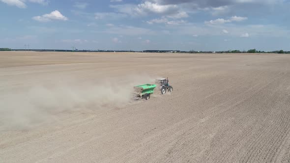 Aerial View  Video of Tractor with Fertilizer Trailer Fertilizes the Field After Planting
