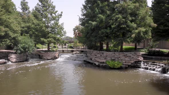 Waterfalls and shade trees make for a pleasant stroll on the San Antonio Riverwalk, in San Antonio, alt