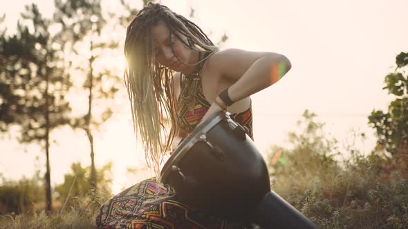 Beautiful Young Hippie Woman with Dreadlocks Playing on Djembe alt