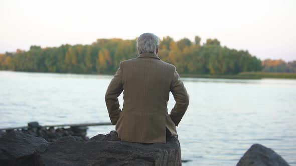 Aged Male Sitting on Stone River Bank, Thinking of Life, Enjoying Nature View alt