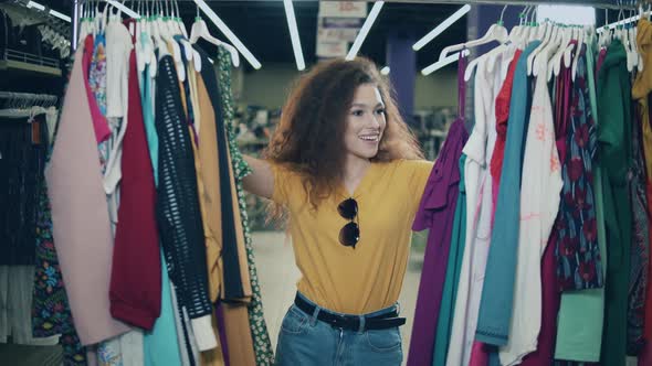 Happy Lady Is Choosing Clothes in a Shop. Happy Female Shopping at Store alt