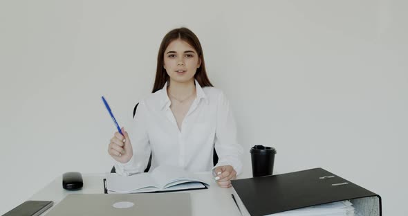 Happy Office Girl Talking with Smile and Pen in Hand for Camera at Workplace alt