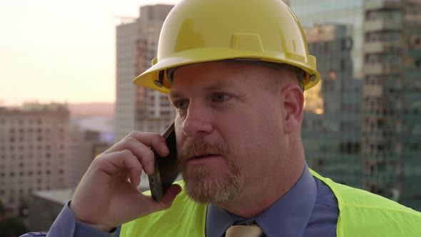 Construction manager on rooftop using cell phone