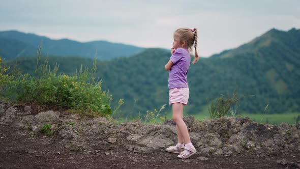 Little Girl in Purple Clothes Thinks on Hill at Eco Resort alt