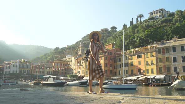 A woman walking wearing hat and backpack purse traveling, Portofino, Italy, luxury resort, Europe alt