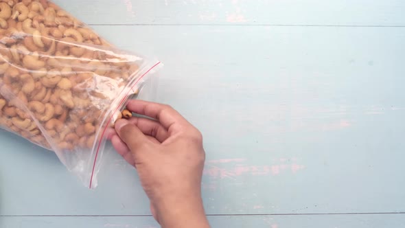 Hand Pick Cashew Nut From a Plastic Bag on Table alt