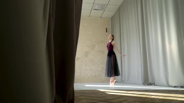 Young Ballerina in Burgundy Swimsuits and Long Black Skirt Rehearsing in a Ballet Studio. Flexible alt