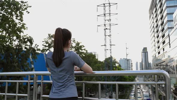 Back view young Asian woman athlete resting after a run.