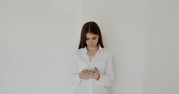 Portrait of Young Girl Typing on the Smartphone on White Background alt