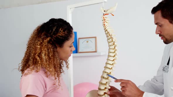 Physiotherapist explaining the spine model to patient alt