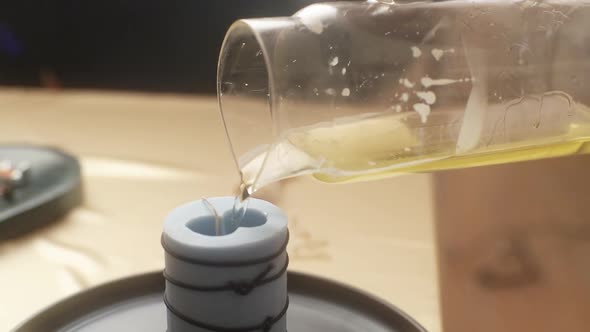 Closeup Cropped Shot of Unrecognizable Female Craftperson Pouring Yellow Liquid Wax From Glass Bowl
