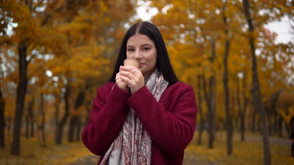 Attractive Woman with Cup of Tea or Coffee Walking Outdoor in Autumn Fall Park