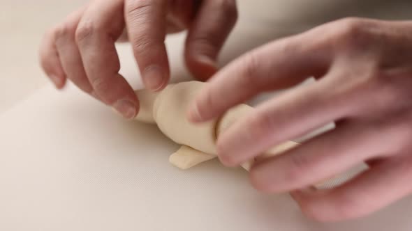 A man rolls raw dough into croissants