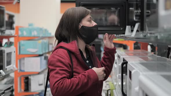 Girl in a Medical Mask Buys a Microwave in a Shop