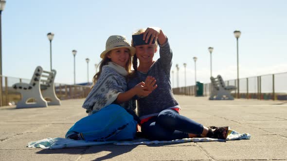 Siblings taking selfie with mobile phone at beach  alt