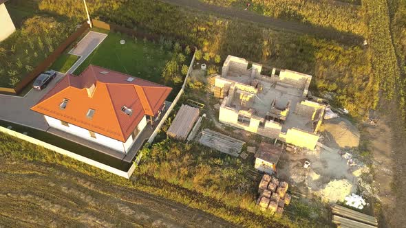 Top Down Aerial View of Two Private Houses One Under Construction with Wooden Roofing Frame and alt