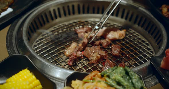 Chief Using the Tong and Turning the Meat on the Grill alt