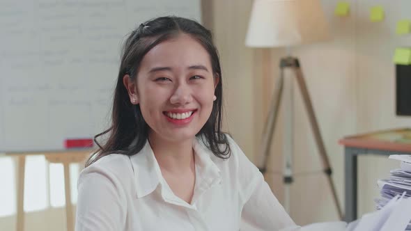 Close Up Of Asian Woman Smiling To Camera While Working With Documents At The Office alt
