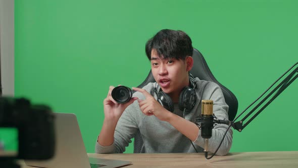 Asian Man Reviewing Camera Len While Shooting Video By Camera On Green Screen Background alt