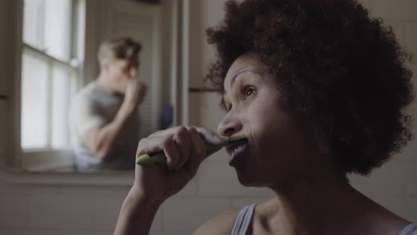 Mixed Race Couple in bathroom brushing teeth