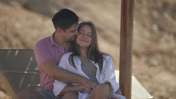Young Pretty Woman is Enjoying Embrace of Her Beloved Man on Beach alt