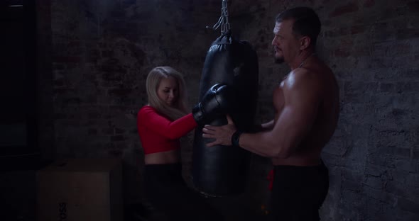 Boxing Coach Giving a Private Training To a Female Athlete Practicing a Punch in Urban Gym