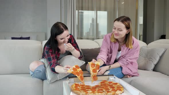 Happy Young Friends Eat Pizza and Talk in a Relaxed Home Environment