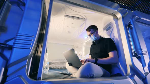 Young Man is Wearing a Face Mask in the Capsule Hotel Room alt