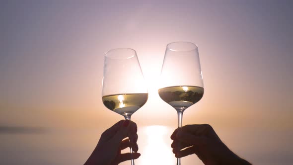 Hands Making Cheers with Wine in Glass Against the Sea alt