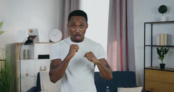 African American Man which Training in Boxing Punches During Home Workout alt