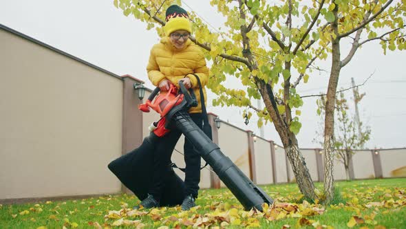 Smiling Boy in Reading Glasses and Yellow Jacket Helping at Backyard on Fall Day alt