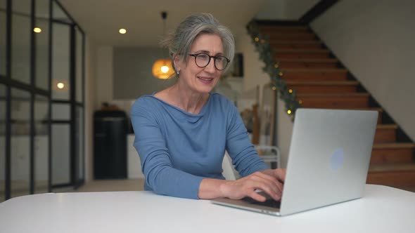 Happy Mature Middle Aged Elderly Woman Looking at Laptop alt