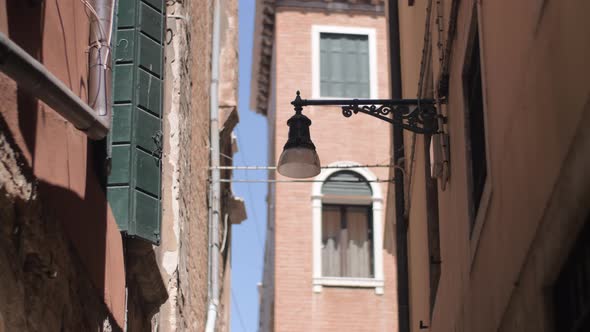 A wall mounted streetlight on a narrow Venice street alt