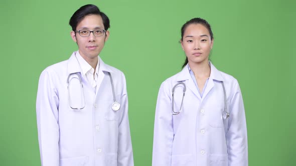 Young Asian Couple Doctors with Fist Raised Together
