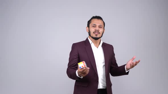 Indian businessman giving brief with rubik's cube in hand alt