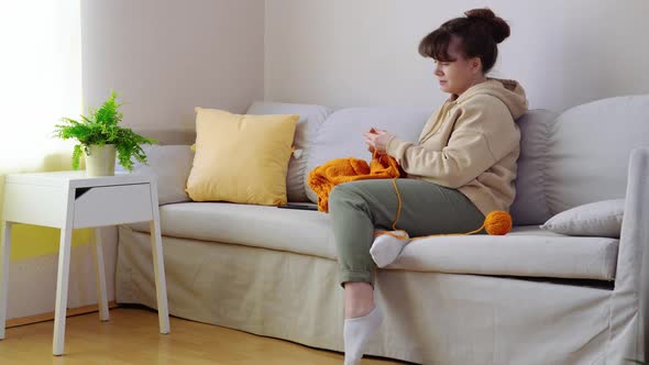 Young Woman Knitting on Sofa at Home alt