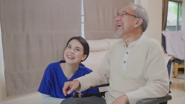 Asian attractive nurse take care mature senior elderly male patient sitting on wheelchair at home. alt