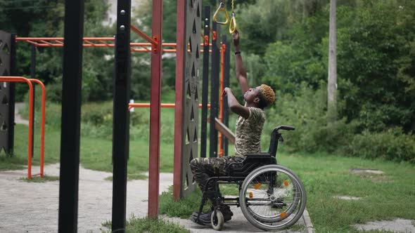 Side View Motivated African American Young Man in Wheelchair Stretching to Sports Equipment in alt